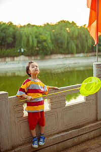 夏日儿童人像夕阳一个男孩护栏旁抬头仰望天空摄影图配图