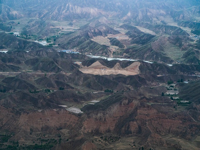 俯瞰沙漠摄影照片_空中航拍白天山脉山丘飞机上俯瞰大地全景摄影图配图