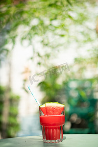 西瓜摄影照片_夏日饮品白天新鲜西瓜汁树阴下文艺唯美桌面背景图摄影图配图