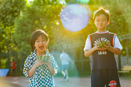 夏日两人人像白天兄弟二人操场逆光下开心的抱着西瓜摄影图配图