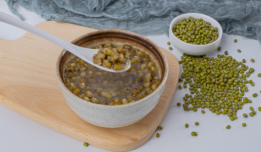 夏日美食背景摄影照片_夏天降暑美食白昼一碗绿豆汤室内餐桌喝绿豆粥摄影图配图