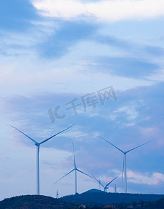 绿色环保风车摄影照片_新能源利用白天风车组山峰云彩风力发电摄影图配图