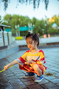 儿童夏日人像白天长发小孩公园里蹲着玩耍摄影图配图