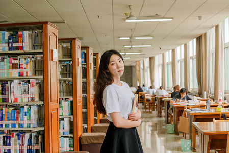 女孩抱着摄影照片_人像白天校园美女图书馆抱着书摄影图配图