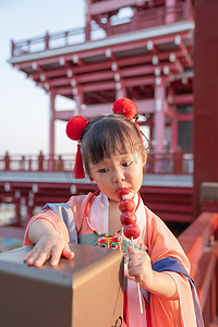 小串糖葫芦摄影照片_吃糖葫芦夕阳儿童建筑吃摄影图配图