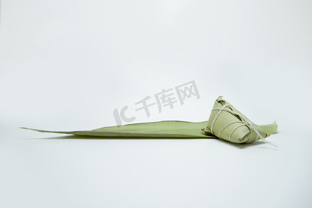 端午节白天粽子粽子叶白色背景布放置粽子摄影图配图