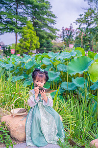 夏至女孩摄影照片_端午荷塘下午儿童荷花塘吃粽子摄影图配图