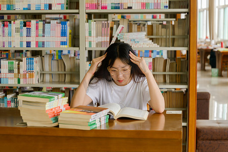 校园人物摄影照片_人像白天大学生图书馆认真思考摄影图配图