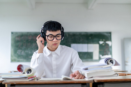 正在教室听音乐自习学习看书的男大学生形象