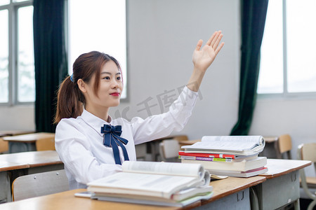 在教室里积极举手的女大学生