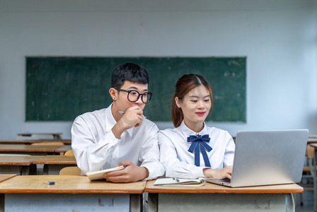 在校园课室里用电脑交流学习的青春男女大学生