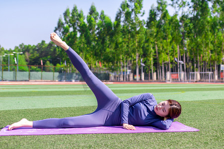减肥瘦身摄影照片_年轻女性在操场瘦身运动瑜伽