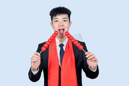 糖葫芦串摄影照片_新年商务男性吃糖葫芦串