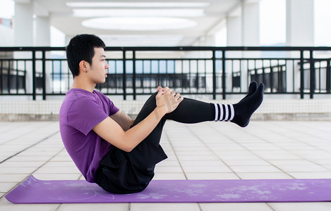 在瑜伽垫上运动健身练习腹肌的年轻男性