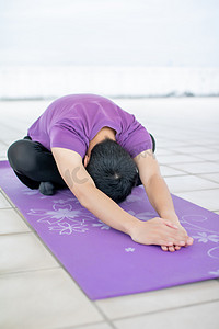 健身摄影照片_在瑜伽垫上运动健身练习的年轻男性