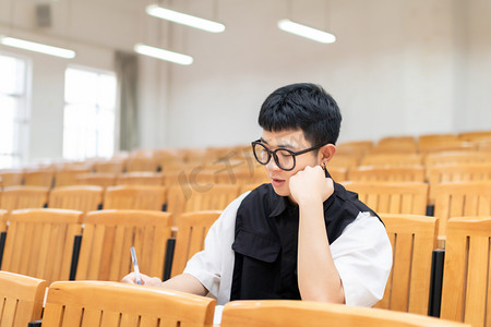 课室里认真做题的男大学生动作