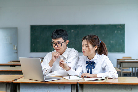 在校园课室里用电脑学习交流的青春男女大学生