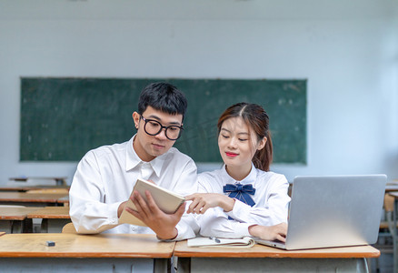 在校园课室里用电脑和笔记本学习的青春男女大学生