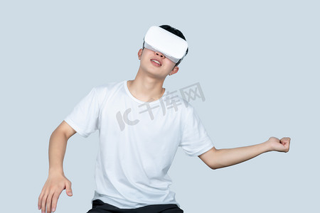 vr场景摄影照片_年轻白t男性戴VR眼镜体验游戏场景