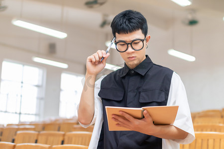 课室里复习笔记的男大学生思考动作