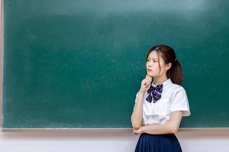 教室黑板前思考的女学生