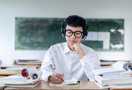课室里听音乐认真做题的男学生
