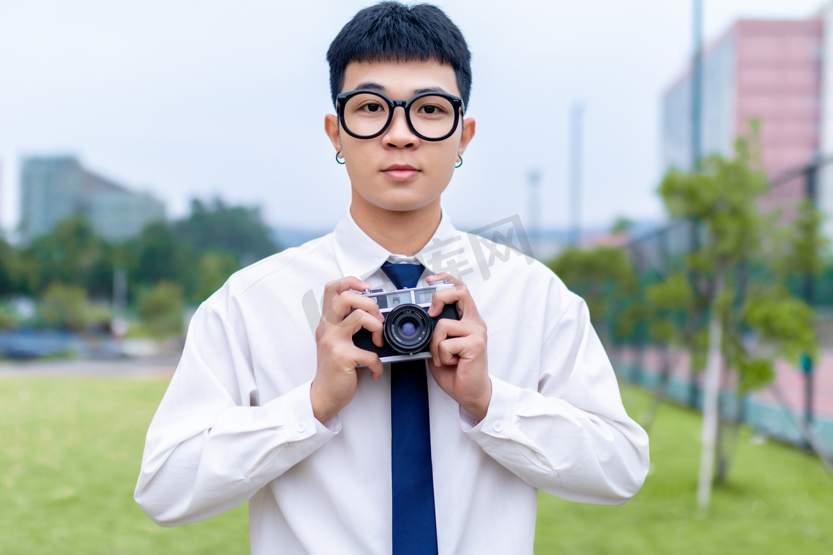 在草地上拿着复古胶卷相机的男大学生高清摄影大图 千库网