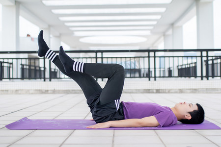 在瑜伽垫上躺着健身练习的年轻男性