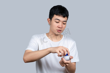 白色短袖青年男子拧开护肤品盖子