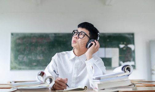 正在教室听歌自习学习看书的男大学生