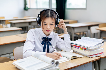 在教室里听歌做题的女大学生