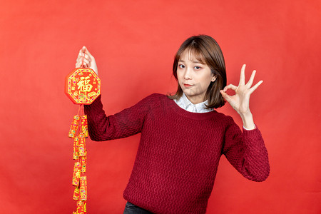 新年甜美女性手拿福字鞭炮ok手势