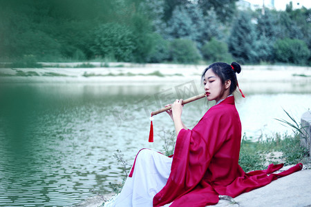 中国风传统文化摄影照片_国潮白天汉服女侠湖边吹笛子摄影图配图