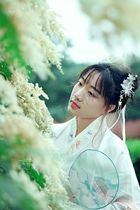 中国风古典传统摄影照片_古风白天古装美女室外赏花摄影图配图