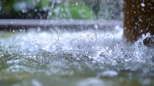 飘落的雨滴摄影照片_实拍唯美夏天大雨雨滴落入水面溅起水花意境