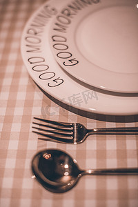 婚礼餐盘卡摄影照片_餐具白天刀叉餐盘在格子桌子上放着摄影图配图
