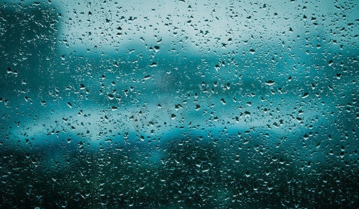 玻璃雨珠摄影照片_夏天风光傍晚窗台玻璃的雨珠室内玻璃上滑落的雨滴摄影图配图