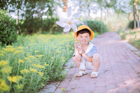 儿童节夏天摄影照片_人物形象夏天男童路边手举风车摄影图配图