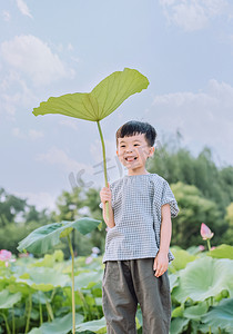 荷叶处暑摄影照片_人物夏天男童荷塘手拿荷叶摄影图配图