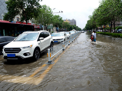 大雨水摄影照片_被淹的城市白天汽车被淹的街道上行驶摄影图配图