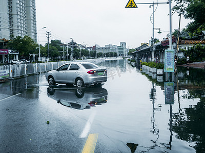 暴雨城市摄影照片_城市大雨白天雨水里的汽车在马路上停着摄影图配图