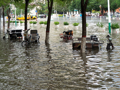 雨后城市摄影照片_被淹的城市白天多辆电动三轮在积水中淹没摄影图配图