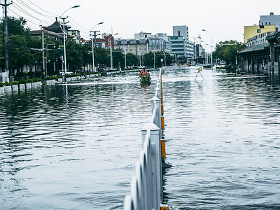 被淹的城市街道骑电动车雨水里骑行摄影图配图