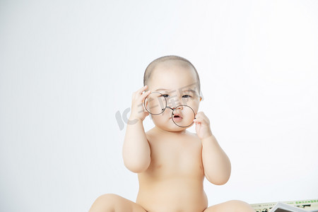 婴儿启蒙教育白天可爱男婴儿室内摘眼镜摄影图配图