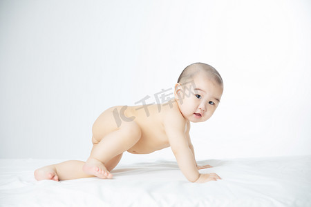 母婴摄影照片_婴儿白天学爬的男婴室内床上爬摄影图配图