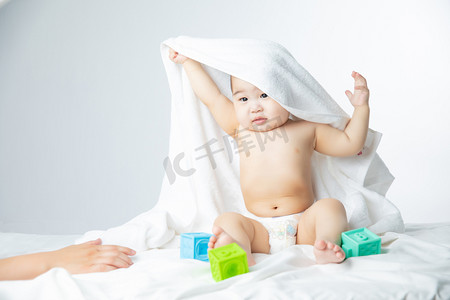 母婴大礼包摄影照片_母婴白天婴儿室内床上抬手摄影图配图