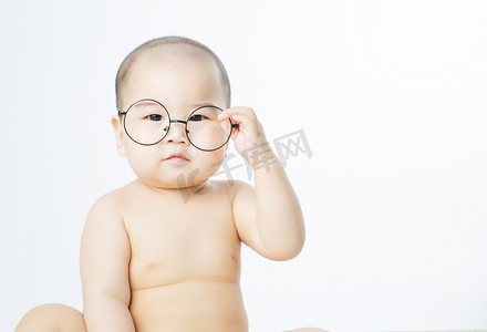 宝宝启蒙摄影照片_婴儿教育白天戴眼镜的可爱男婴室内扶眼镜摄影图配图
