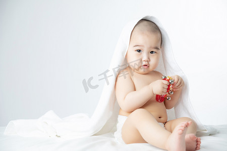床上摄影照片_婴儿白天玩玩具的男婴儿室内床上坐着摄影图配图