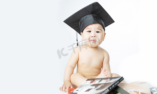 母婴教育摄影照片_启蒙教育白天坐在书堆里的男婴儿室内抬头摄影图配图