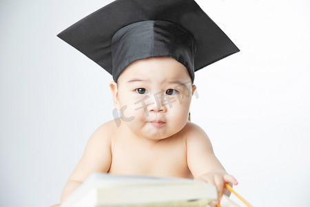 婴儿启蒙教育白天戴着博士帽子的男婴室内坐着摄影图配图